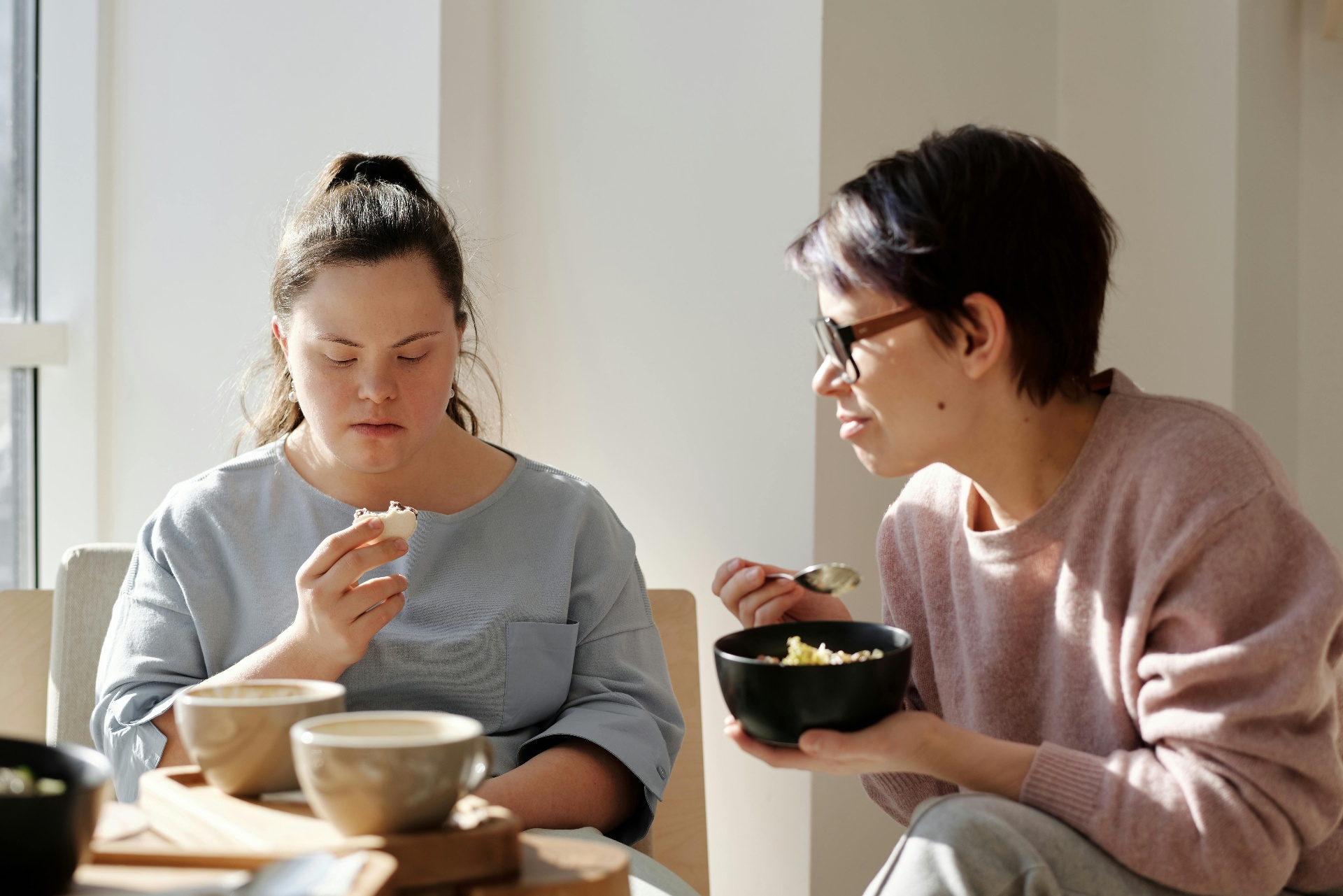 Carer sharing a meal with a young woman at home