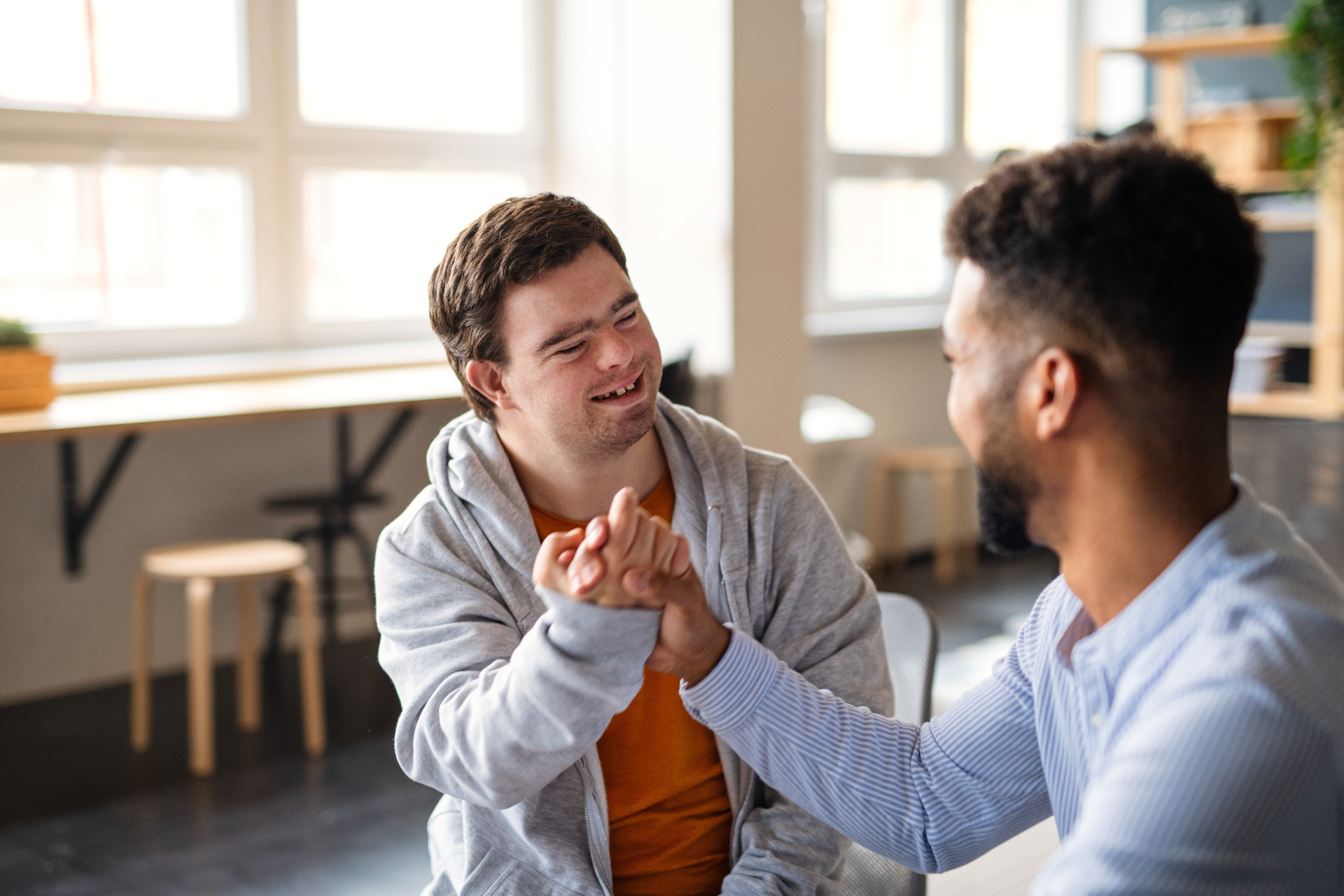 Support worker greeting a young man with a warm handshake